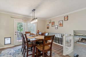 Dining space featuring a textured ceiling, wood finished floors, and ornamental molding
