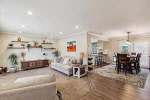 Living area with ornamental molding, wood finished floors, recessed lighting, and a textured ceiling