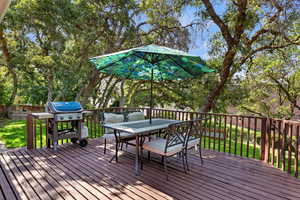 Deck with outdoor dining space, a grill, and a lawn