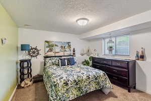 Carpeted bedroom with a textured ceiling and baseboards