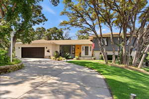 Split level home with an attached garage, a front yard, and driveway