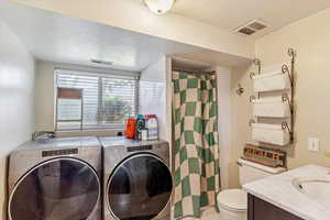 Laundry area featuring a textured ceiling, washing machine and clothes dryer, and light tile patterned floors