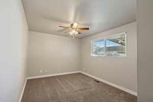 Carpeted spare room featuring baseboards and a ceiling fan