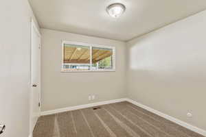 Unfurnished room with baseboards and dark carpet