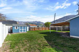 Fenced backyard with a storage unit and a mountain view