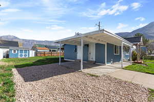 Rear view of house featuring a mountain view, a storage shed, a carport, and a patio area