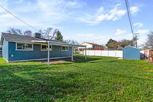 Rear view of house with a fenced backyard, a storage shed, and roof with shingles