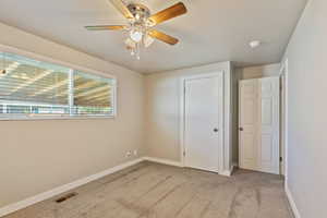 Unfurnished bedroom featuring light colored carpet and ceiling fan
