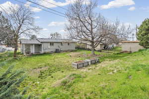 Rear view of property featuring a yard, a vegetable garden, and a patio area