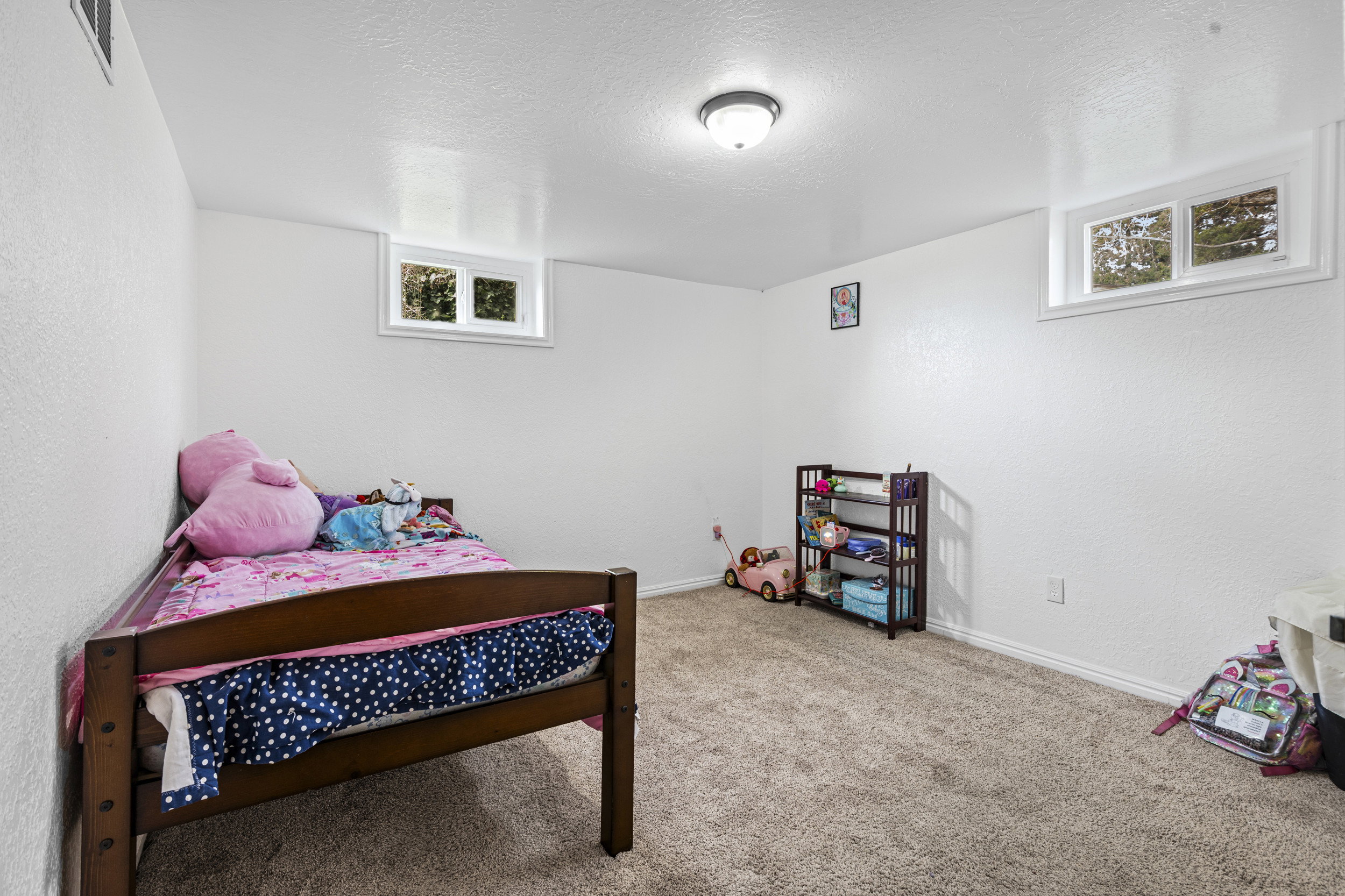 Bedroom featuring a textured ceiling, light colored carpet, a textured wall, and multiple windows