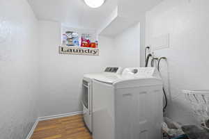 Laundry area with a textured wall, dark wood-type flooring, a textured ceiling, and separate washer and dryer
