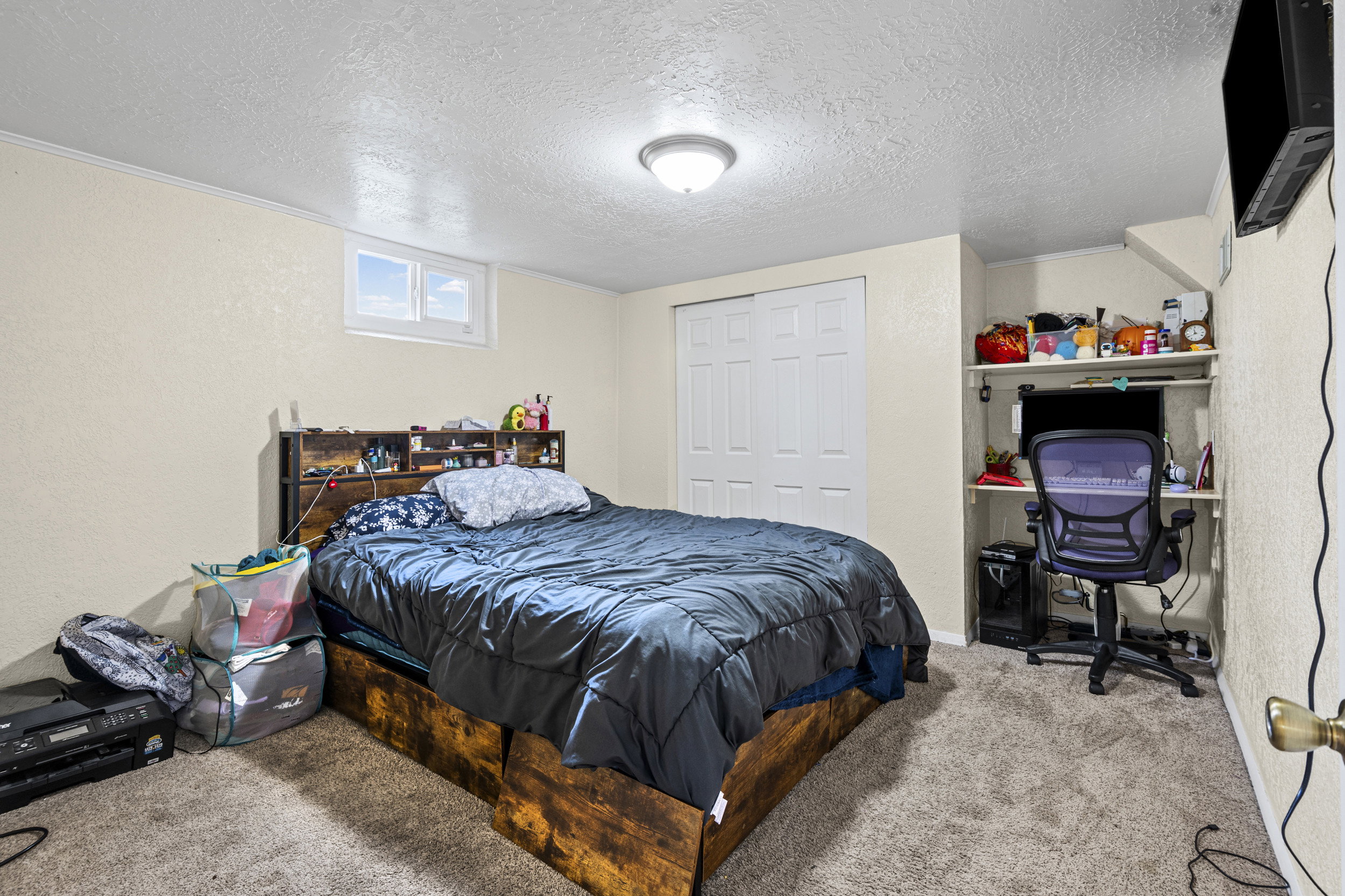 Bedroom with carpet, an office area, a textured ceiling, a closet, and a textured wall