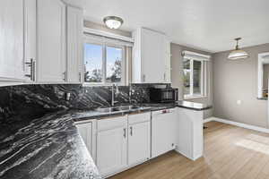 Kitchen with white cabinets, dishwasher, pendant lighting, and light wood finished floors