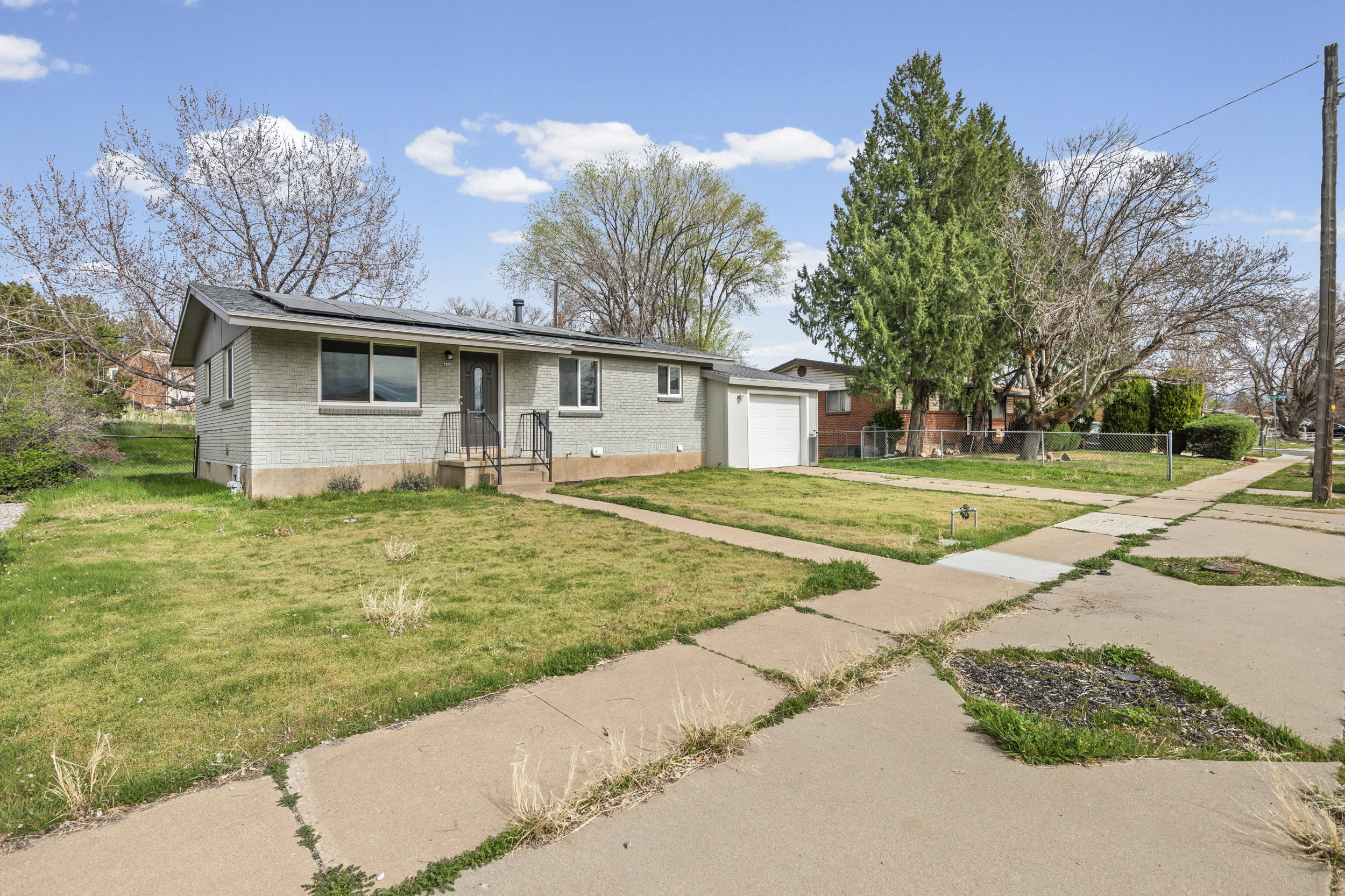 View of front of house featuring brick siding, roof mounted solar panels, driveway, and an attached garage