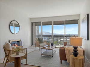 Living room with a warm lit fireplace, a mountain view, wood finished floors, and a wainscoted wall