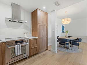 Kitchen with stainless steel electric range, extractor fan, light wood-type flooring, and light countertops