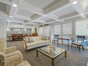 Carpeted living area featuring recessed lighting, coffered ceiling, and crown molding