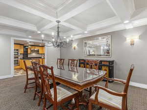 Dining room with light carpet, suspended lighting, coffered ceiling, and ornamental molding