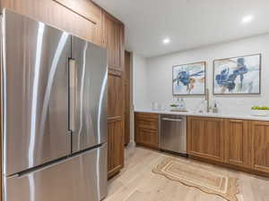 Kitchen featuring stainless steel appliances, light wood finished floors, wood finish cabinets, and recessed lighting
