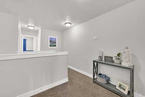 Hallway with carpet flooring and an upstairs landing
