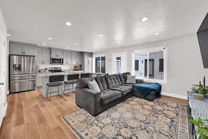 Living area with a textured ceiling, light wood-style floors, and recessed lighting