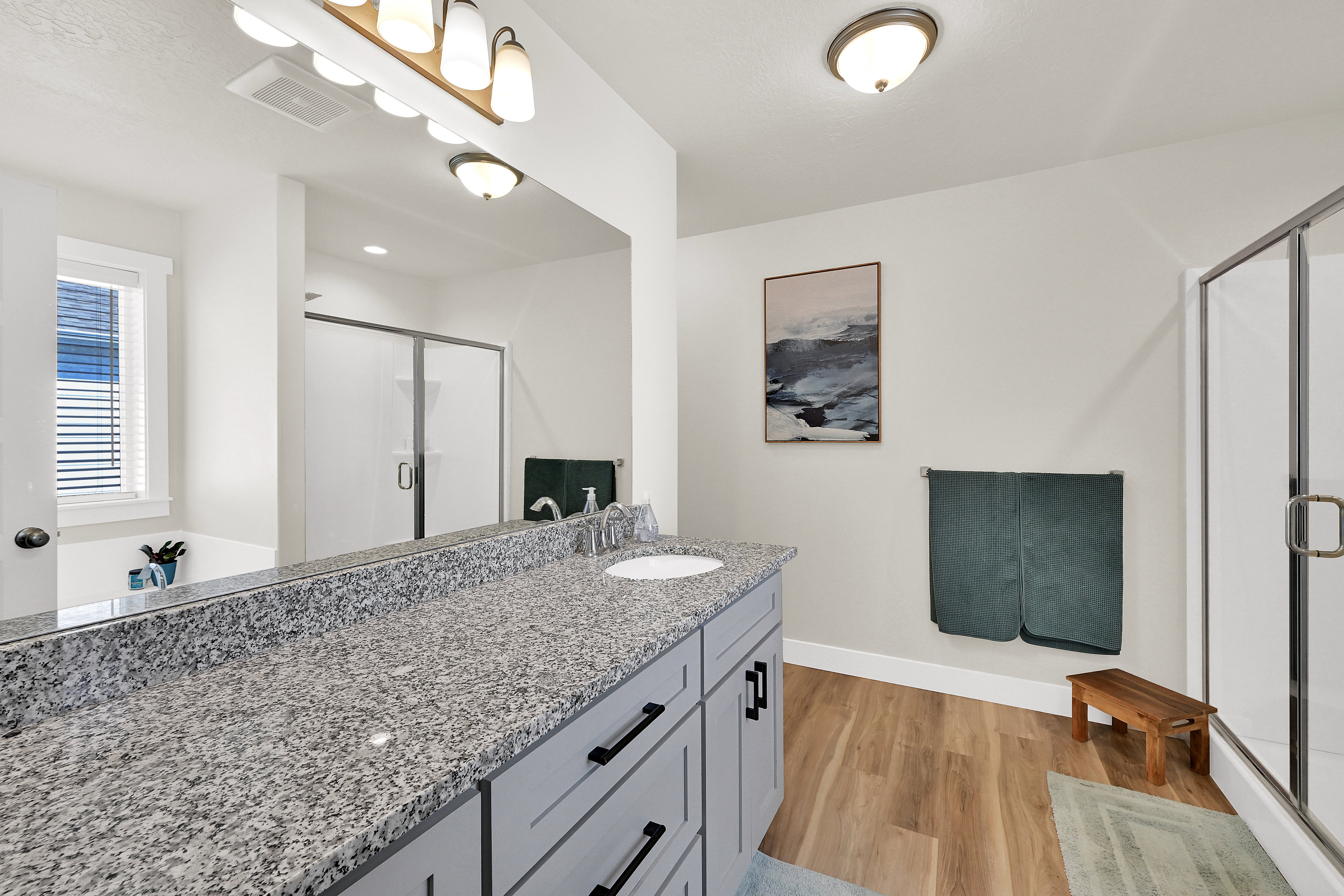 Full bath with vanity, a shower stall, and light wood finished floors