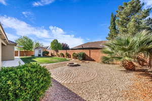 Fenced backyard with a shed, a patio area, and a fire pit