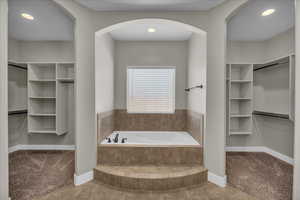 Full bath featuring a spacious closet, carpet flooring, recessed lighting, and a bath