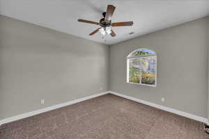 Carpeted empty room with baseboards and a ceiling fan