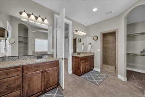 Bathroom with a spacious closet, two vanities, a walk in shower, and light tile patterned flooring