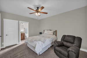 Carpeted bedroom with a ceiling fan and ensuite bath