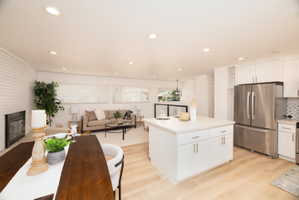 Kitchen featuring freestanding refrigerator, open floor plan, white cabinets, and a center island