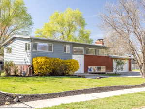 Raised ranch featuring brick siding, a chimney, a garage, and driveway