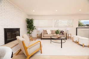 Living room with recessed lighting, wood finished floors, and a brick fireplace