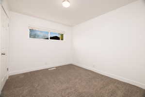 Unfurnished bedroom with dark colored carpet and baseboards