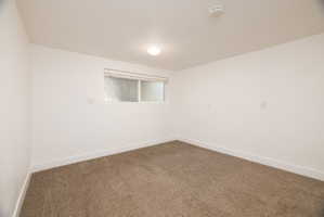 Carpeted spare room with baseboards and a smoke detector