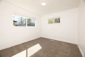 Empty room featuring dark carpet and baseboards