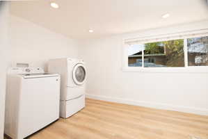 Laundry room with light wood finished floors, washing machine and clothes dryer, and recessed lighting