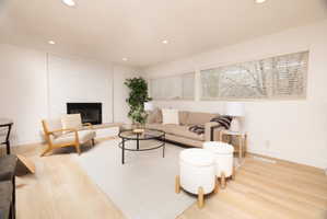 Living room with wood finished floors, recessed lighting, and a brick fireplace
