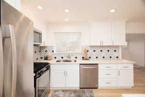 Kitchen with stainless steel appliances, white cabinetry, recessed lighting, light stone countertops, and healthy amount of natural light