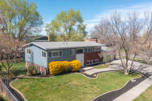 View of front of house with a chimney, a front lawn, a shingled roof, and driveway