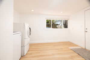 Laundry area with light wood-style floors, separate washer and dryer, and recessed lighting