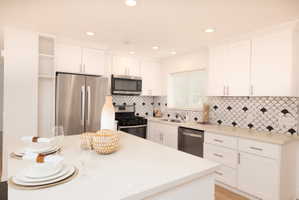 Kitchen featuring stainless steel appliances, white cabinets, a kitchen island, open shelves, and recessed lighting