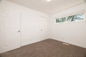 Unfurnished room with baseboards and dark colored carpet