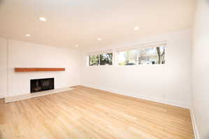 Unfurnished living room featuring recessed lighting, light wood-type flooring, and a large fireplace