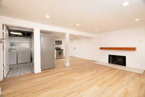 Unfurnished living room with washing machine and dryer, light wood-style flooring, a fireplace, and recessed lighting
