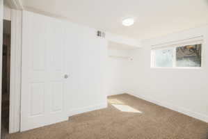 Empty room featuring baseboards and light carpet