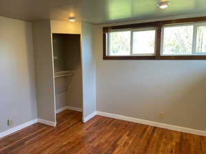 Unfurnished bedroom featuring baseboards and dark wood-style floors