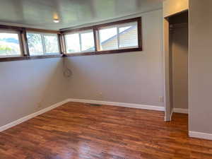 Unfurnished bedroom with baseboards and dark wood-style floors