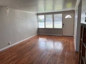 Foyer featuring dark wood-style flooring and crown molding